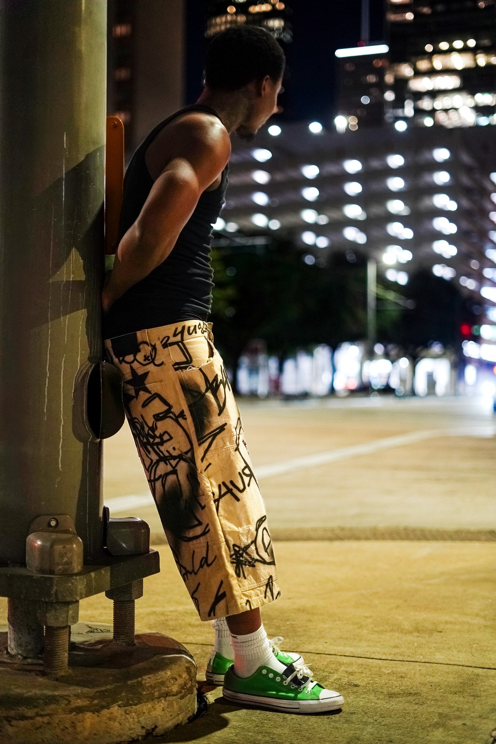 Model wearing Graffiti Carpenter Capris on a nighttime street, viewed from the side